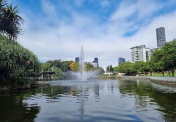 Blue skies and water fountain shooting upwards in lake at Roma Street Parklands.