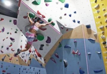 Wall Walkers Bouldering woman hanging from bouldering wall.